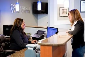 A woman talking to the receptionist at the front desk